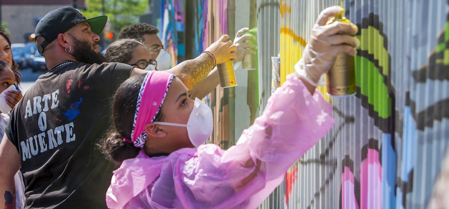 Participants spray paint a mural as part of WHEDco's ArtsFest.